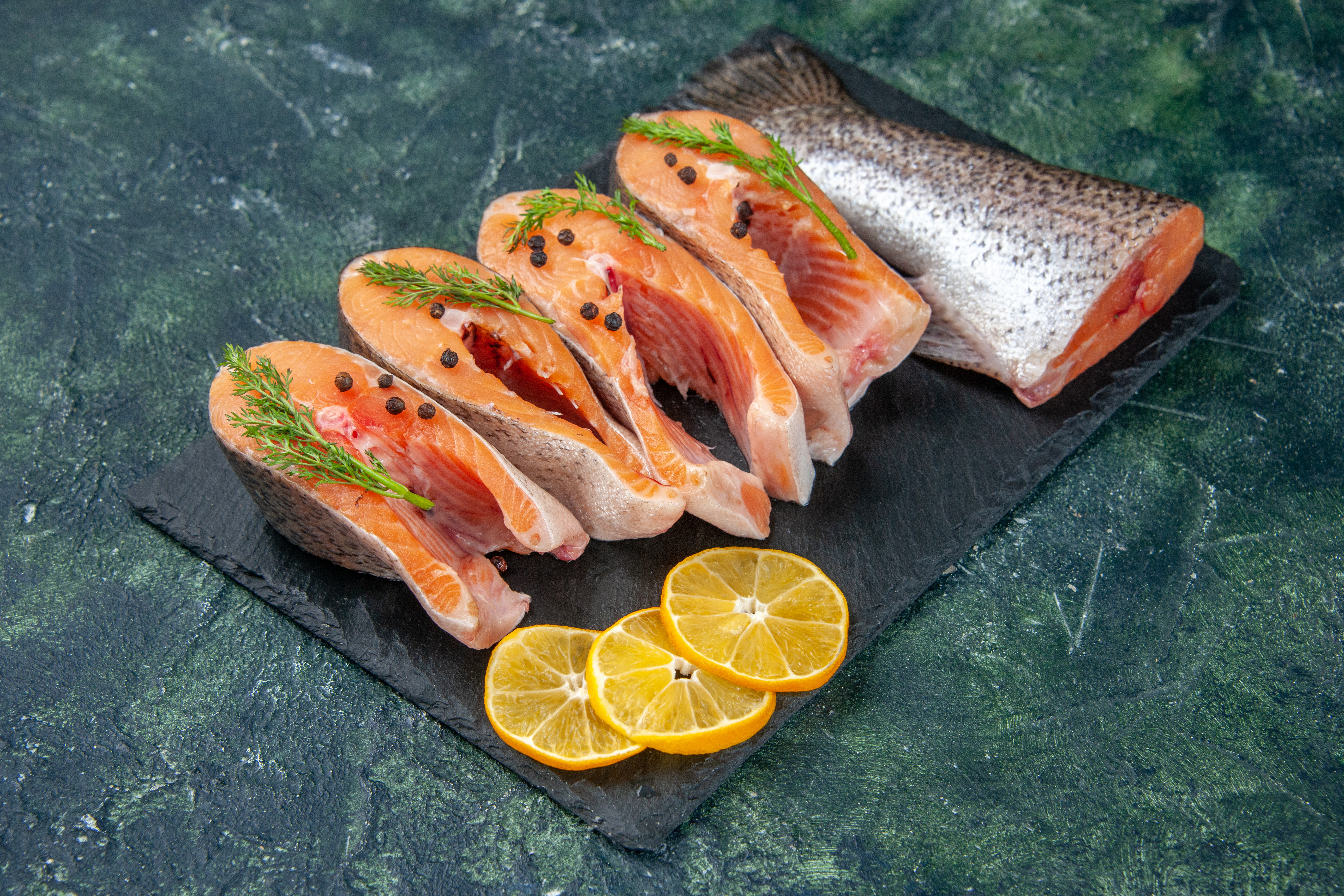side-view-fresh-raw-fishes-greens-pepper-lemon-slices-dark-color-tray-blue-black-mix-colors-table (1).jpg
